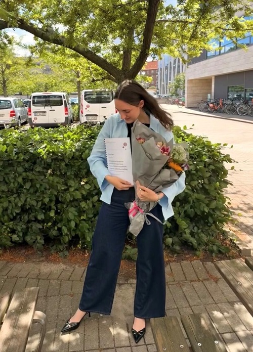 Kandidat i mikrobiologi, Urszula Oko, med blomster og sit eksamensbevis.